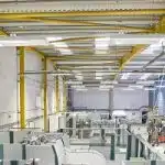 Worker operating machinery in factory that manufactures aluminium light fittings