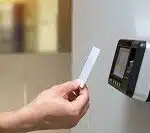 Close up hand of security man using the ID card to scanning at the access control system machine for identity verification to open the door or check attendance.