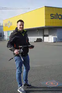 Sita Mitarbeiter hält eine Drohne in der Hand.