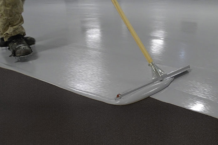 Applikation der ableitfähigen Epoxidharz-Bodenbeschichtung MC‑DUR ChemProtect auf einem Industriebetonboden mit Rakel