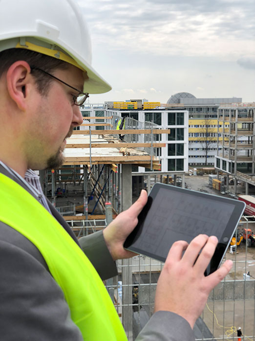 CEO Timur Ripke von COMAN nutzt auf einer Baustelle ein Tablet zur digitalen Baudokumentation