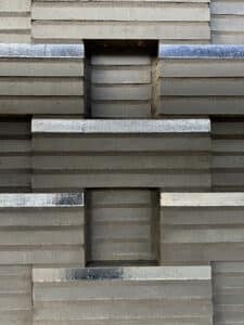 Close-up of gray concrete blocks arranged in a geometric, stepped pattern with rectangular recesses at the center and along the edges.